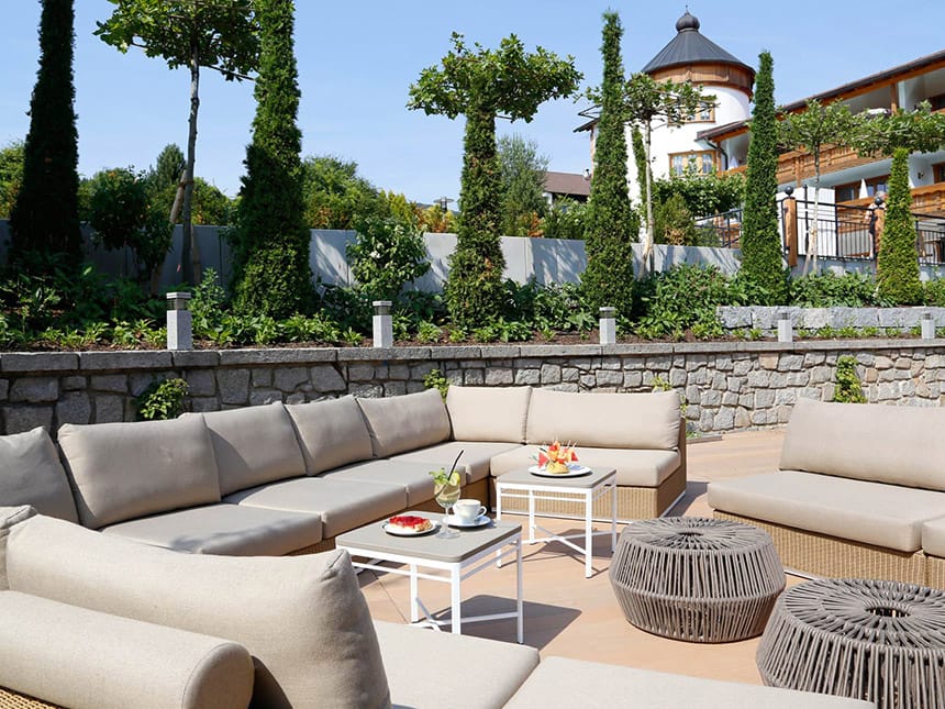 Hotelterrasse bei Sonnenschein mit Loungemöbeln und Kaffe und Kuchen auf dem Tisch