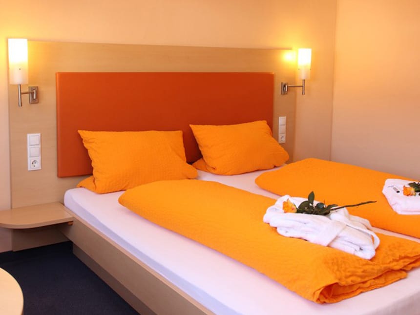 Classic Doppelzimmer mit Doppelbett, Leselampen und oranger Bettwäsche