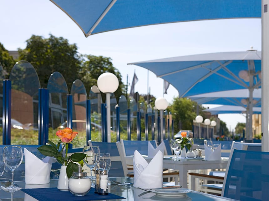 Hotel Terrasse mit blauen Sitzmöbeln und Sonnenschirmen 
