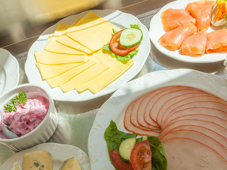 Speisen am Buffet wie Käse, Lachs, gekochter Schinken und Heringssalat