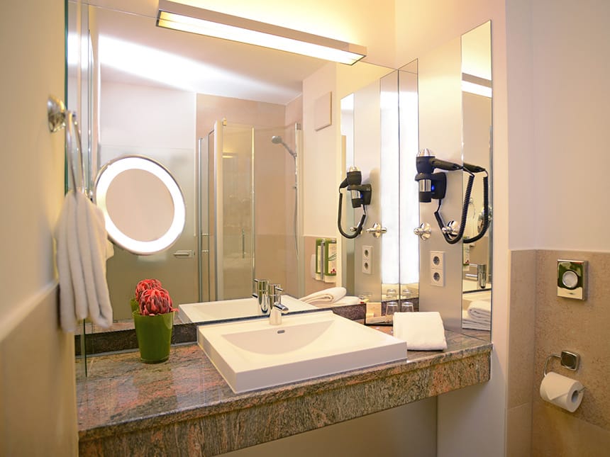 Badbereich mit Wand und Kosmetikspiegel, Föhn und Waschtisch