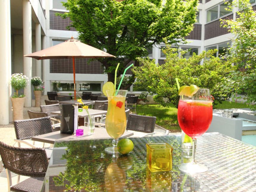 Terrasse und Innenhof mit Tischen, Stühlen, Sonnenschirm und Cocktails auf dem Tisch