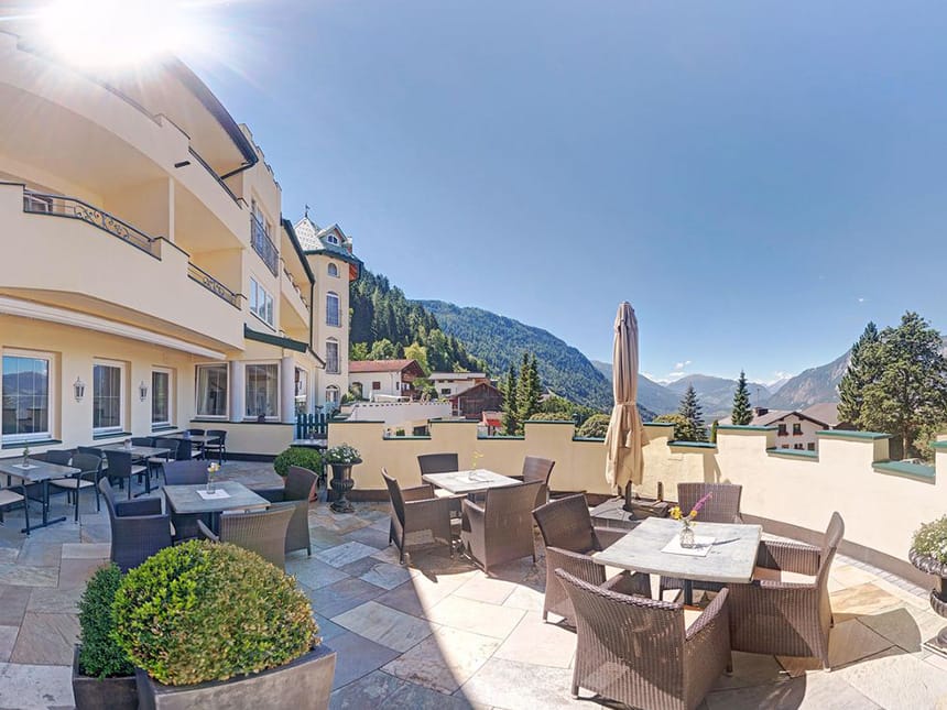 Hotelveranda bei Sonnenschein mit Korbmöbeln und Sonnenschirm