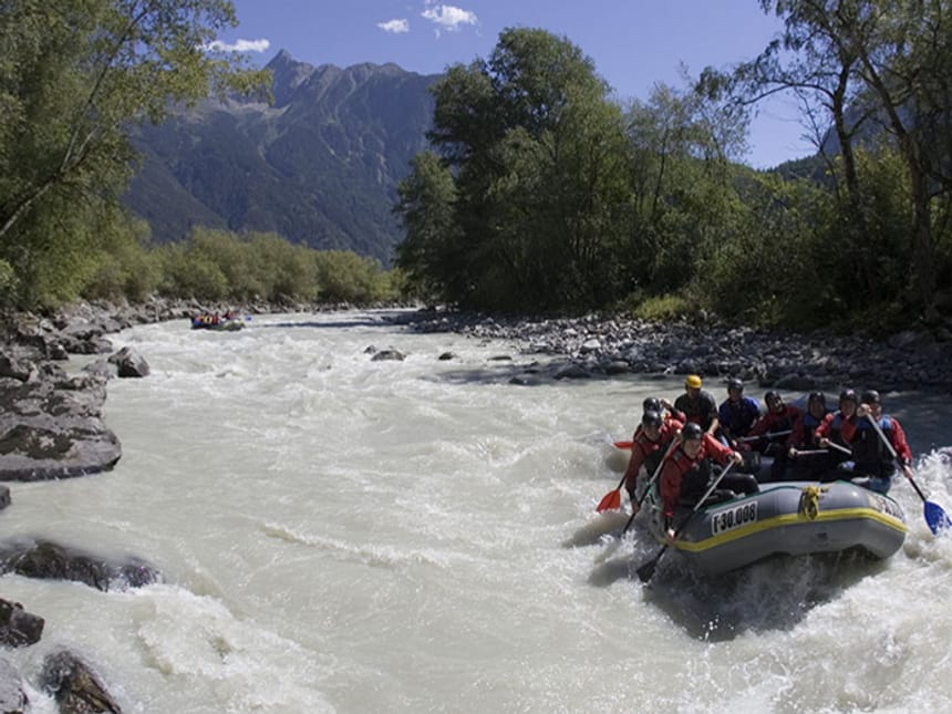 Wildwasser Rafting mit Bott und Bergen im Hintergrund