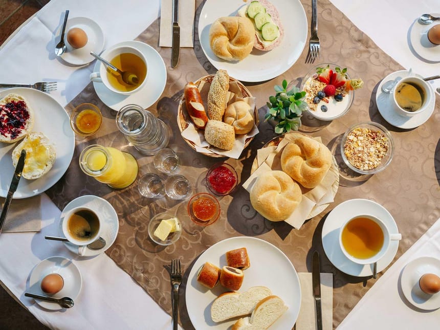 Gedeckter Frühstückstisch mit Brötchen, Tee, Kaffee, Marmelade und Müsli