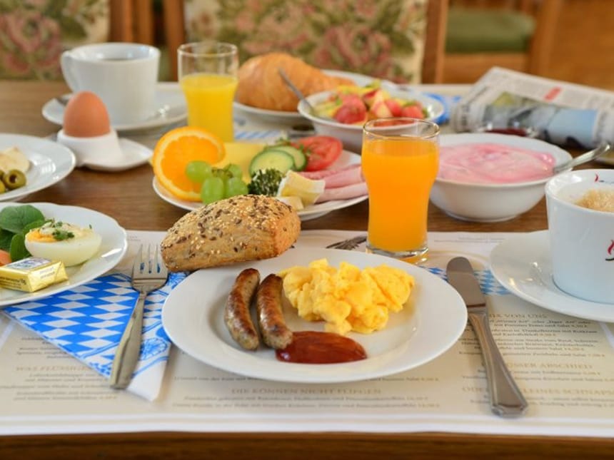 gedeckter Frühstückstisch mit Rührei, Obst, Saft, Müsli und Kaffee