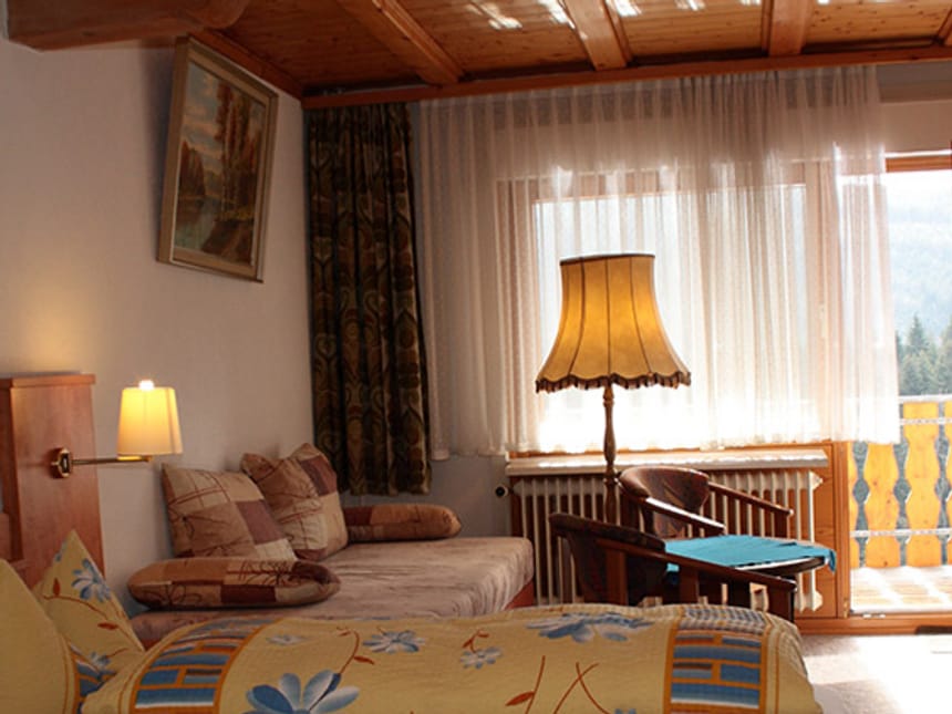 Standard Doppelzimmer mit Doppelbett, Couch, Sessel, Stehlampe und Tisch