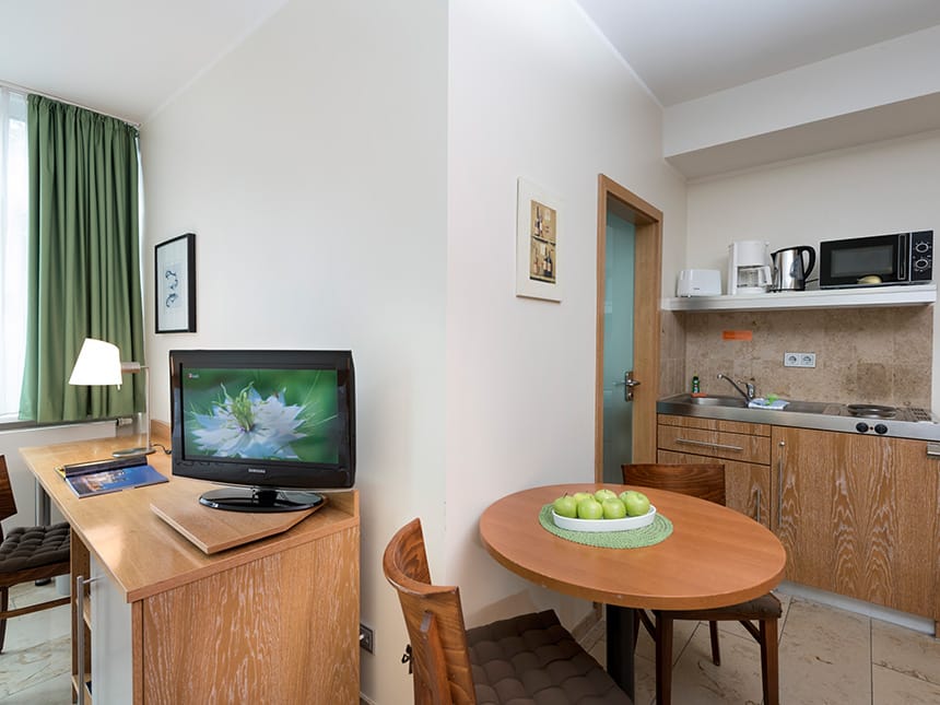 Studio Apartement mit Küchenzeile, Tisch, TV, Stuhl und Schreibtisch