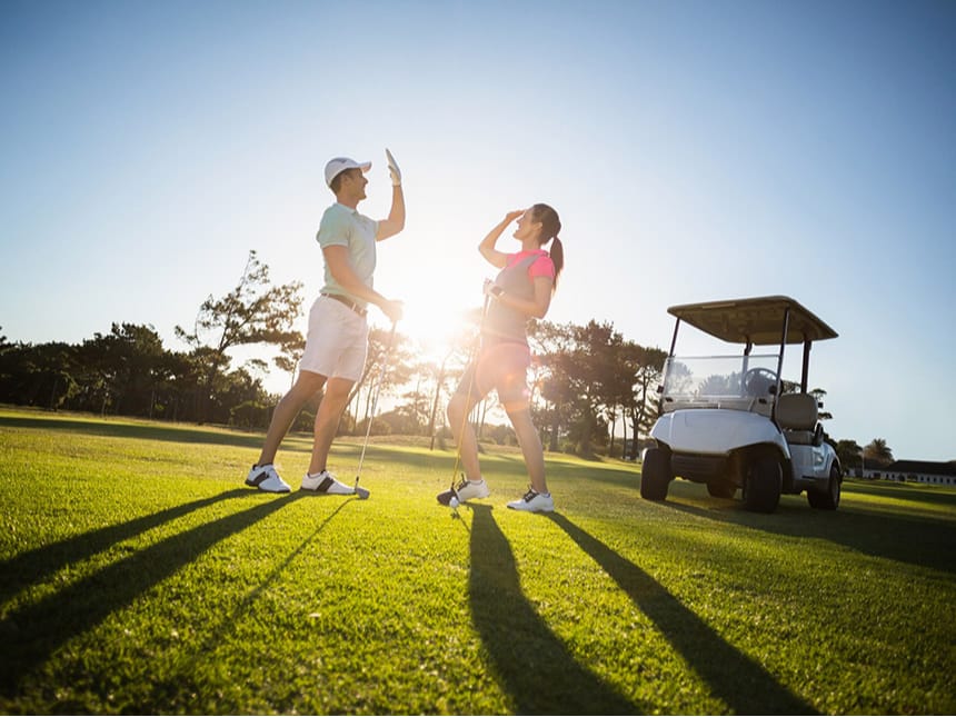 Mann und Frau auf dem Golfplatz mit Golf-Cart