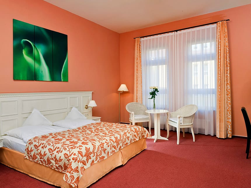 Komfort Doppelzimmer rot mit zwei weißen Stühlen, Tisch und Doppelbett