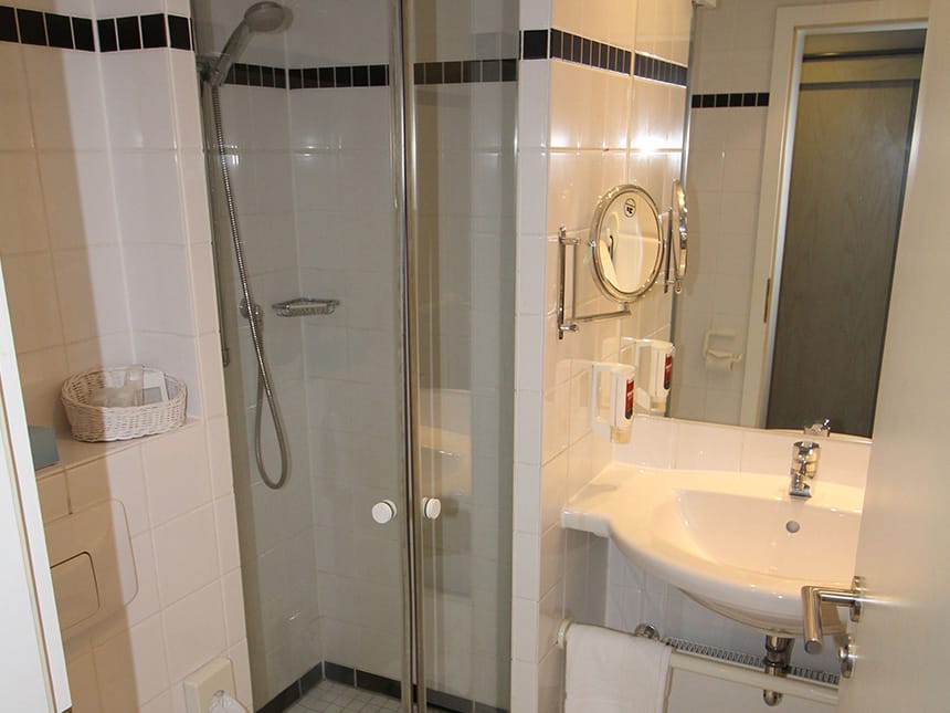 Badbereich mit Dusche, Waschtisch, Kosmetikspiegel und Seifenspender