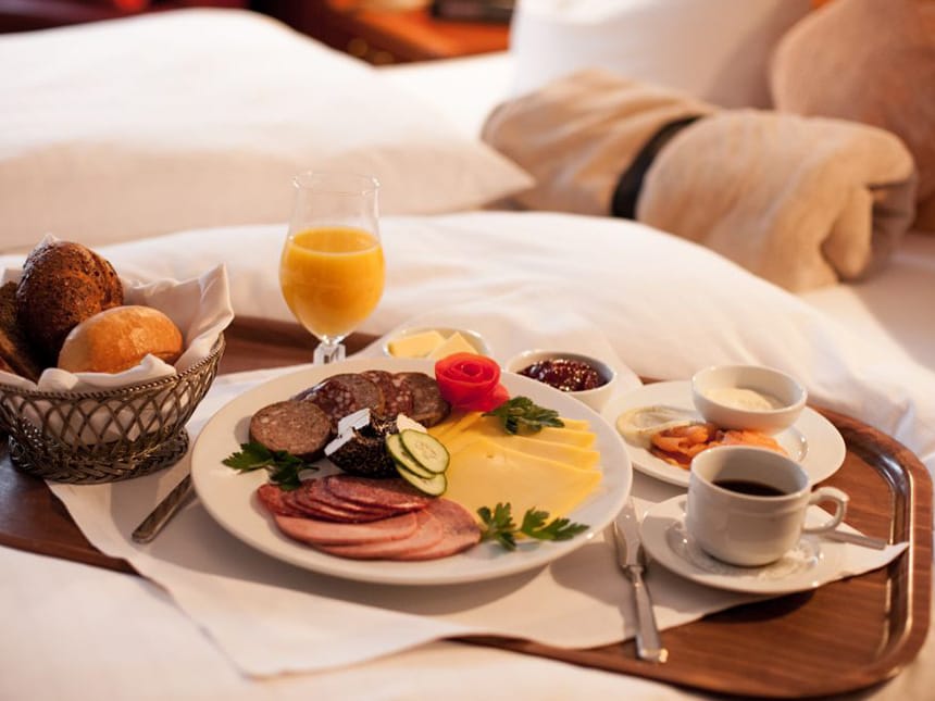 Frühstück am Bett mit Brötchen, Wurst und Käseauswahl, Kaffee, Lache Marmelade und Saft