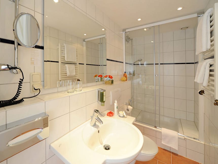 Badbereich mit Duschwanne, Wand- und Kosmetikspiegel, Waschtisch und WC