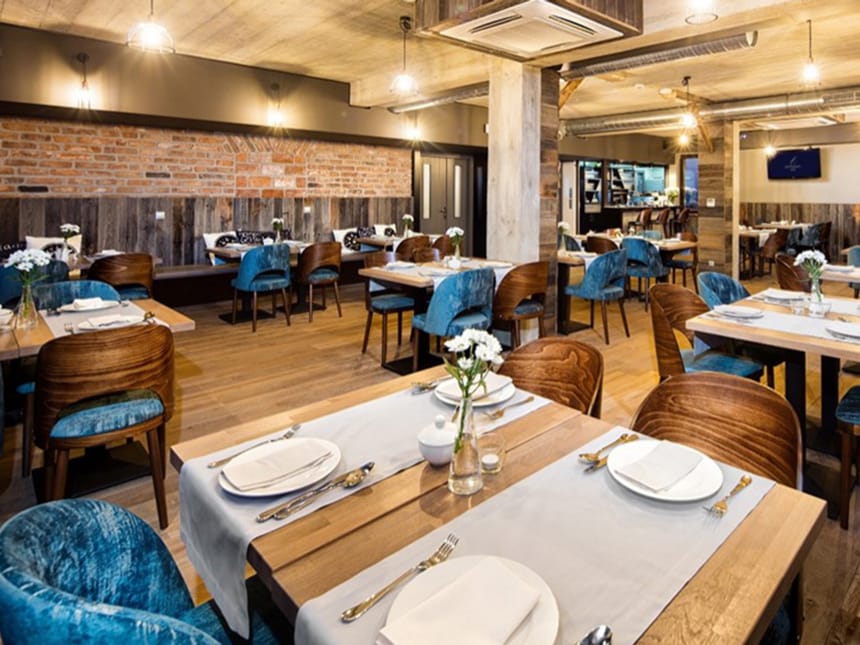 gemütlich eingerichtetes Restaurant mit Holzstühlen und festllich eingedeckten Tischen