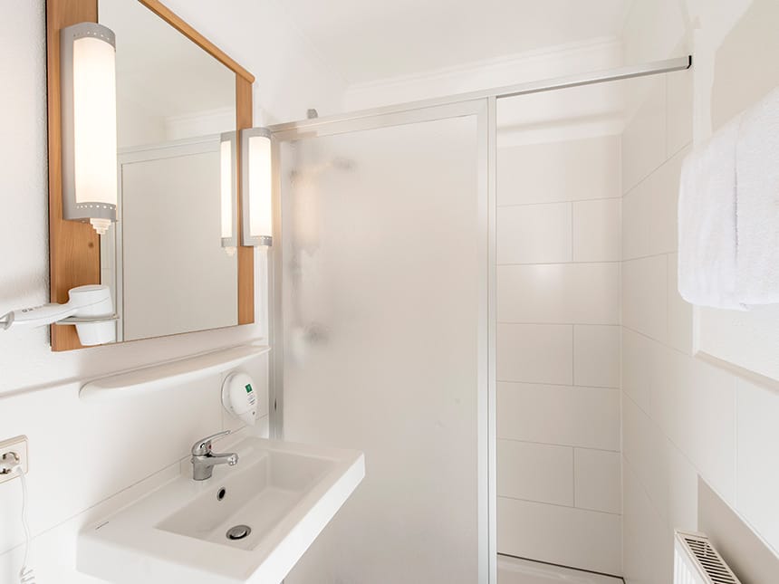 Bad im Doppelzimmer mit Dusche, Waschtisch, Wandspiegel und Föhn