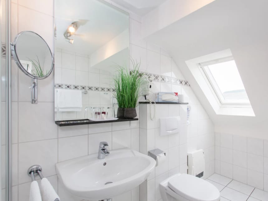 Badezimmer mit Spiegel, Kosmetikspiegel, WC, Spülstein und Dachfenster