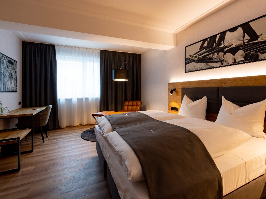 Standardzimmer mit Couch, Tisch, Doppelbett und Balkon