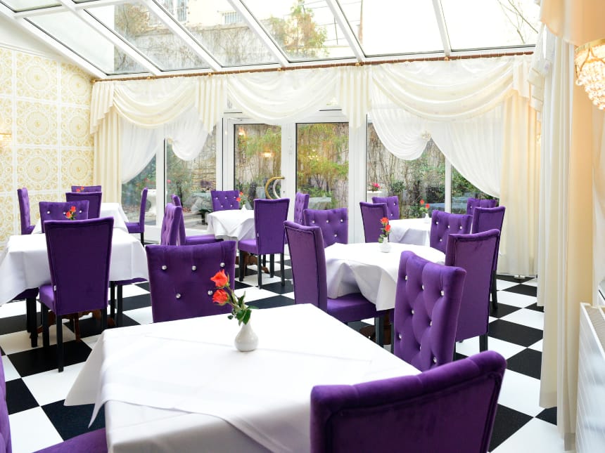 Großes Cafe mit vielen Tischen und violetten Akzenten